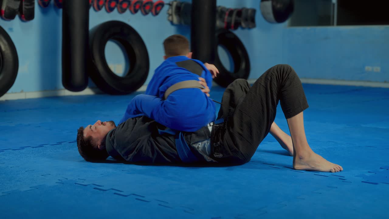 Adult and child training Brazilian Jiu-Jitsu on the mat