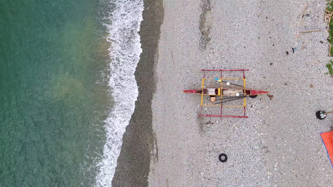 Tradizionale barca filippina banka che riposa su una spiaggia di ciottoli vicino a calme acque turchesi, vista dall'alto