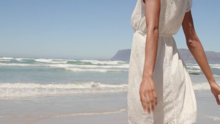 Low angle view of young African american woman having fun on beach in the sunshine 4k