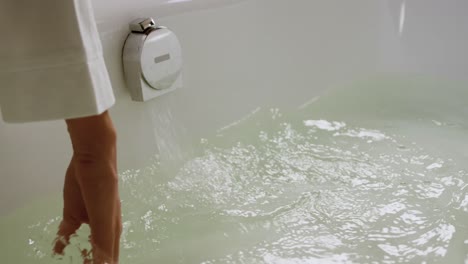 vista de cerca de la mujer probando la temperatura del baño en el hotel