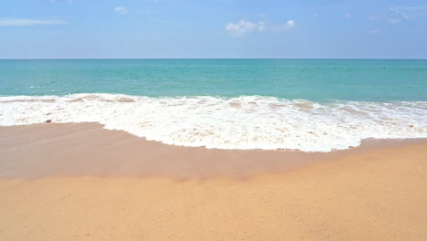 slow-motion of a large wave spreading across the golden sand of a deserted beach