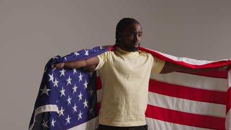 Studio Portrait Shot Of Man Wrapped In American Flag Celebrating 4th July Independence Day