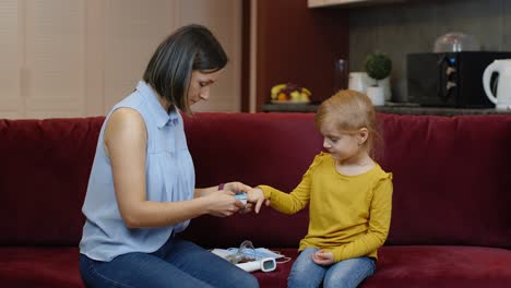 Mother-measuring,-monitoring-oxygen-saturation-with-digital-pulse-oximeter-of-her-daughter-at-home