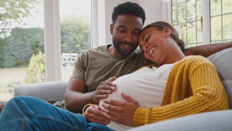 Pregnant-Army-Couple-With-Woman-Sitting-Next-To-Husband-As-He-Touches-Her-Stomach