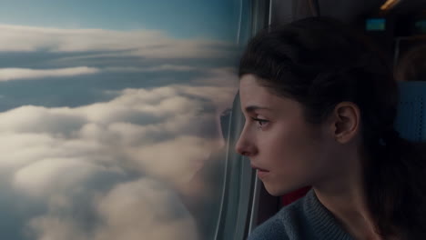young woman looking out of window at clouds during travel