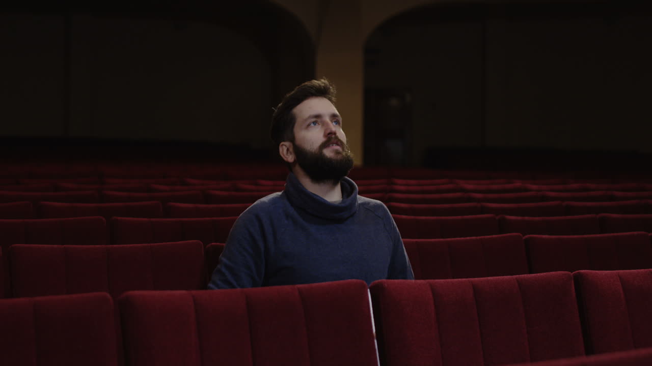 hombre viendo una película o una obra de teatro en un teatro