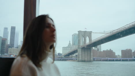 woman on a boat tour in new york city with the brooklyn bridge
