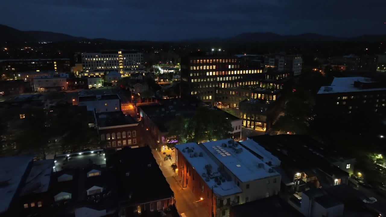 Aerial establishing shot of lighting city buildings of Charlottesville with mystic dark night sky. Illuminated street and windows of office complex in Charlottesville, Virginia, USA. cinematic shot.