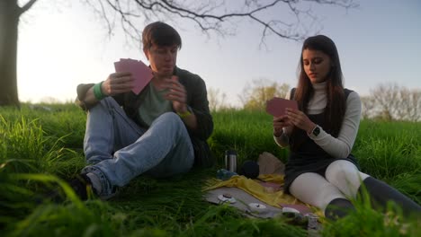 couple playing cards in a park at sunset