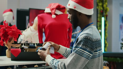 close up shot of cheerful african american worker arranging formal neckties in christmas decorated luxurious shopping mall clothing store, making sure they are ready for arriving clients