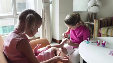 madre pintando las uñas de los pies de su hija