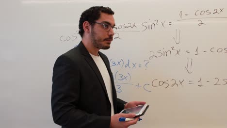 teacher writing on whiteboard, seen from behind