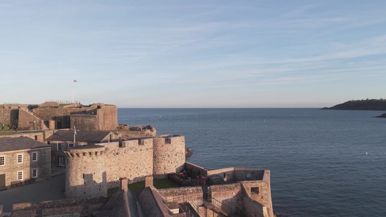 Castello Cornet, St Peter Port, Guernsey, Isole del Canale. Primo piano delle fortificazioni e dei bastioni nella Baia di Havelet sotto il sole splendente, con vista sul mare calmo verso St Martin's Point e uccelli che volano