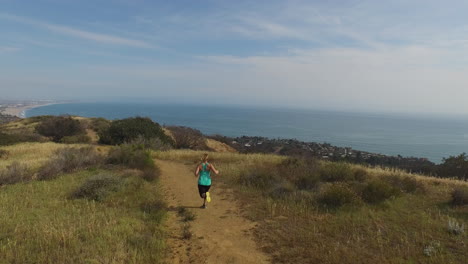 Mujer-Corriendo-En-La-Cima-De-Una-Montaña-Sobre-El-Océano