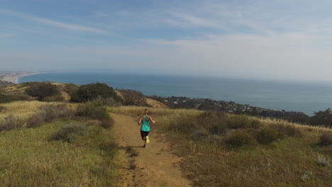 mujer corriendo en la cima de una montaña sobre el océano