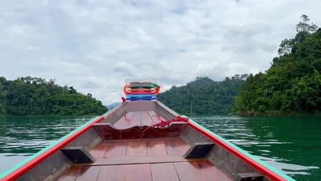 boat glides khao sok lake, showcasing front, water, jungle, and mountains