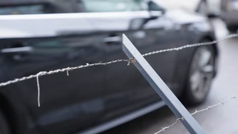 Stacheldrahtzaun-Gegen-Vorbeifahrende-Autos-In-Der-Stadtstraße---Nahaufnahme