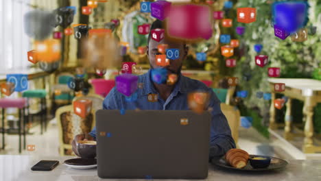 multiple digital icons floating against african american man using laptop