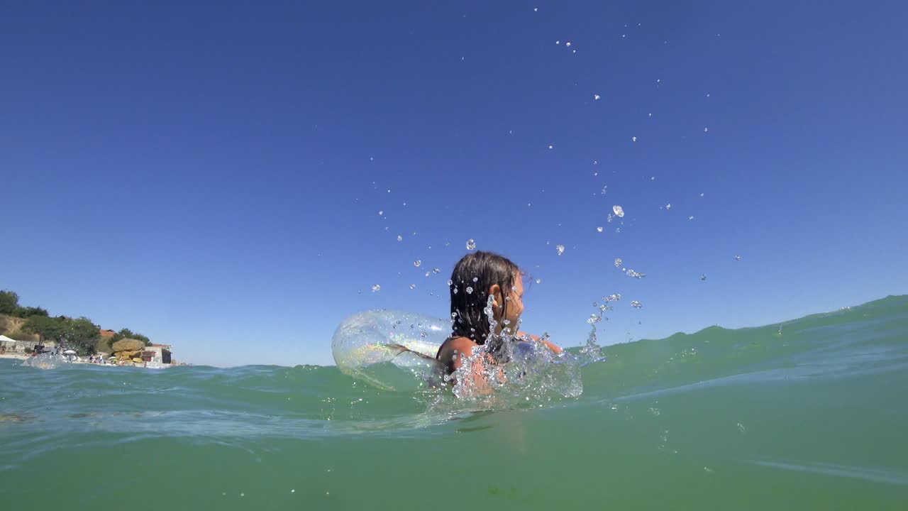 소녀는 고무 반지 위에서 바다에서 수영합니다.