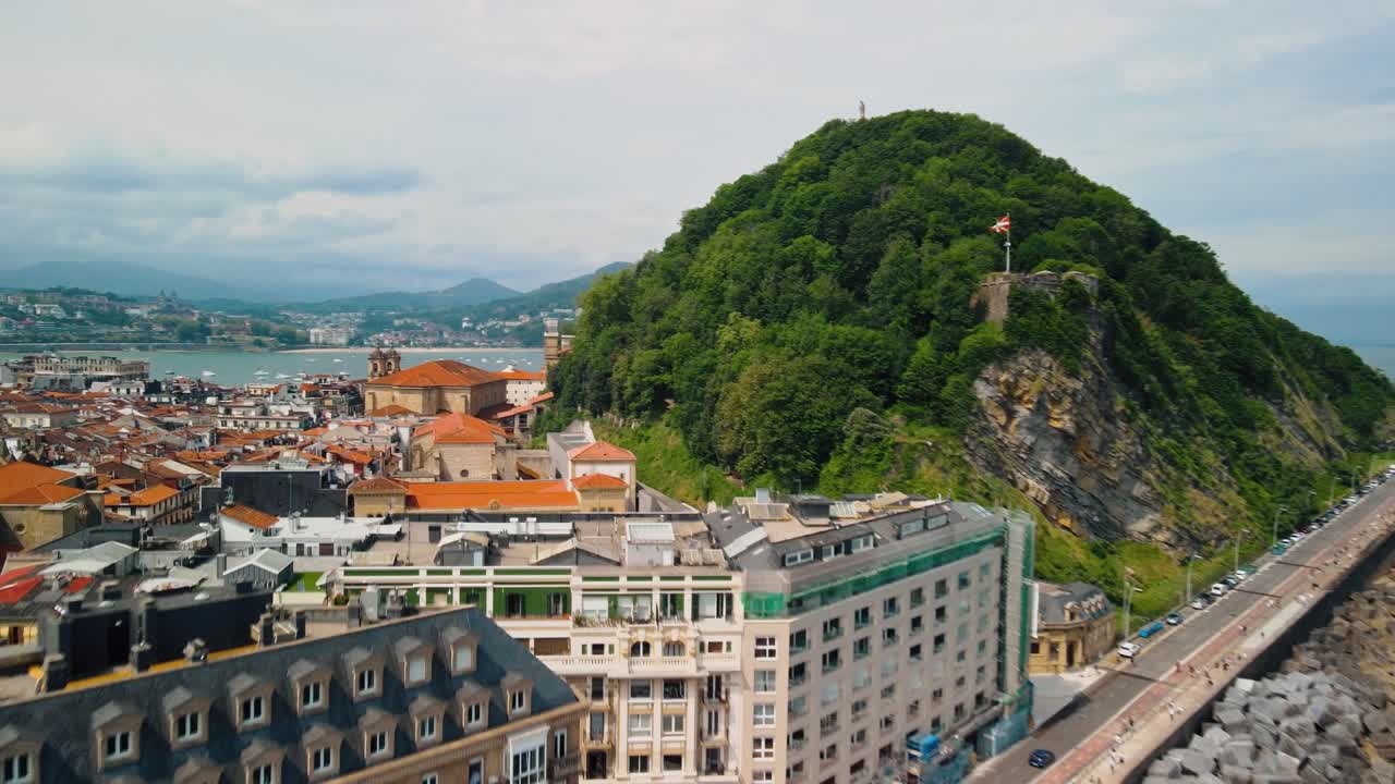 스페인 의 산 세바스티안 의 활기찬 오렌지색 건물 정면 과 울창 한 식물성 해안 언덕