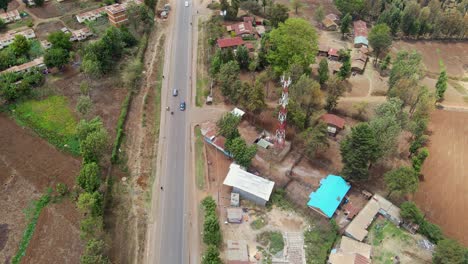 Aerial-view-of-a-town-and-sunlit-fields,-golden-hour-in-rural-Africa---tracking,-drone-shot