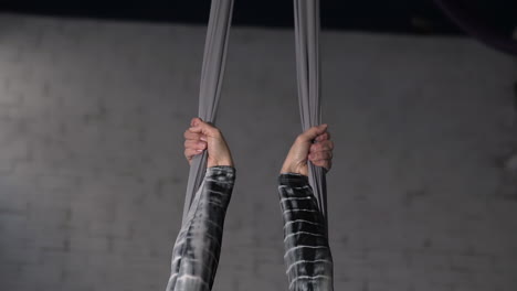 close up of the hands of a circus acrobat grabbing the silks and pulling herself up