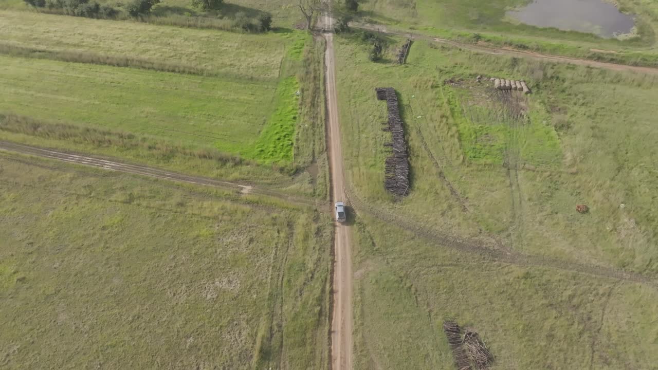 Drone shot of a pick up truck traveling along a dirt road on a farm in the midlands of South Africa