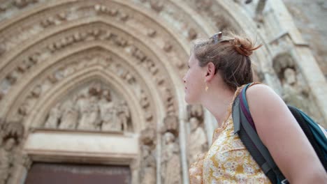 reisende frau, die das schöne äußere der basílica de santa maria in der gemeinde castelló d&#39;empúries, spanien, betrachtet und schätzt – aufnahme aus der tiefwinkelperspektive