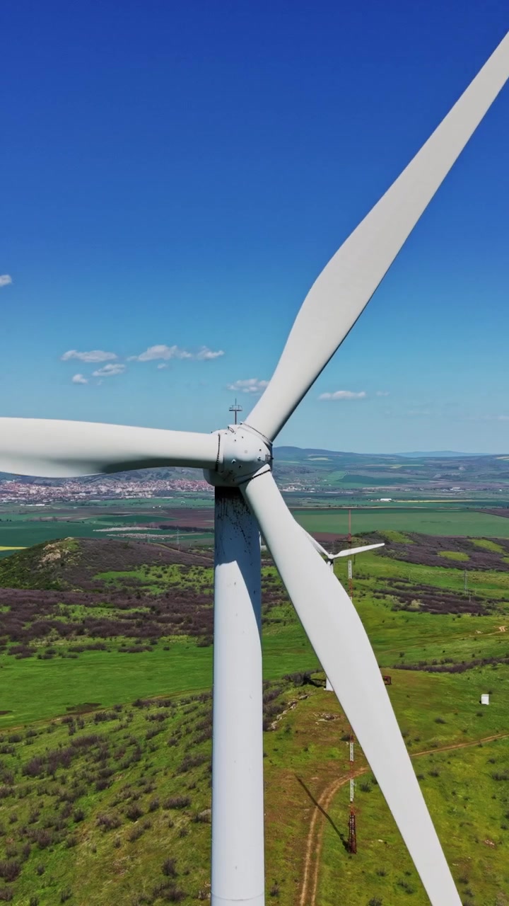 Le turbine eoliche si ergono alte in campi verdi vicino a una piccola città durante il giorno