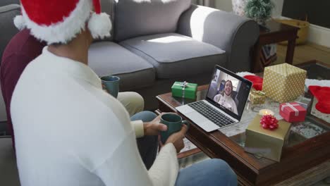 Biracial-father-and-son-using-laptop-for-christmas-video-call-with-happy-woman-on-screen