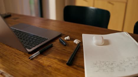 home office workspace with laptop, notebook, and earbuds