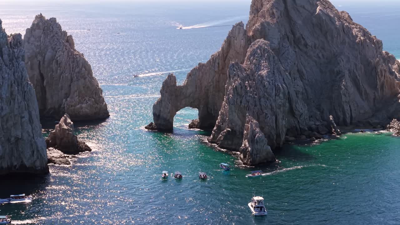 Aerial over the famous Arch of Cabo San Lucas with group of people on boats during the daytime