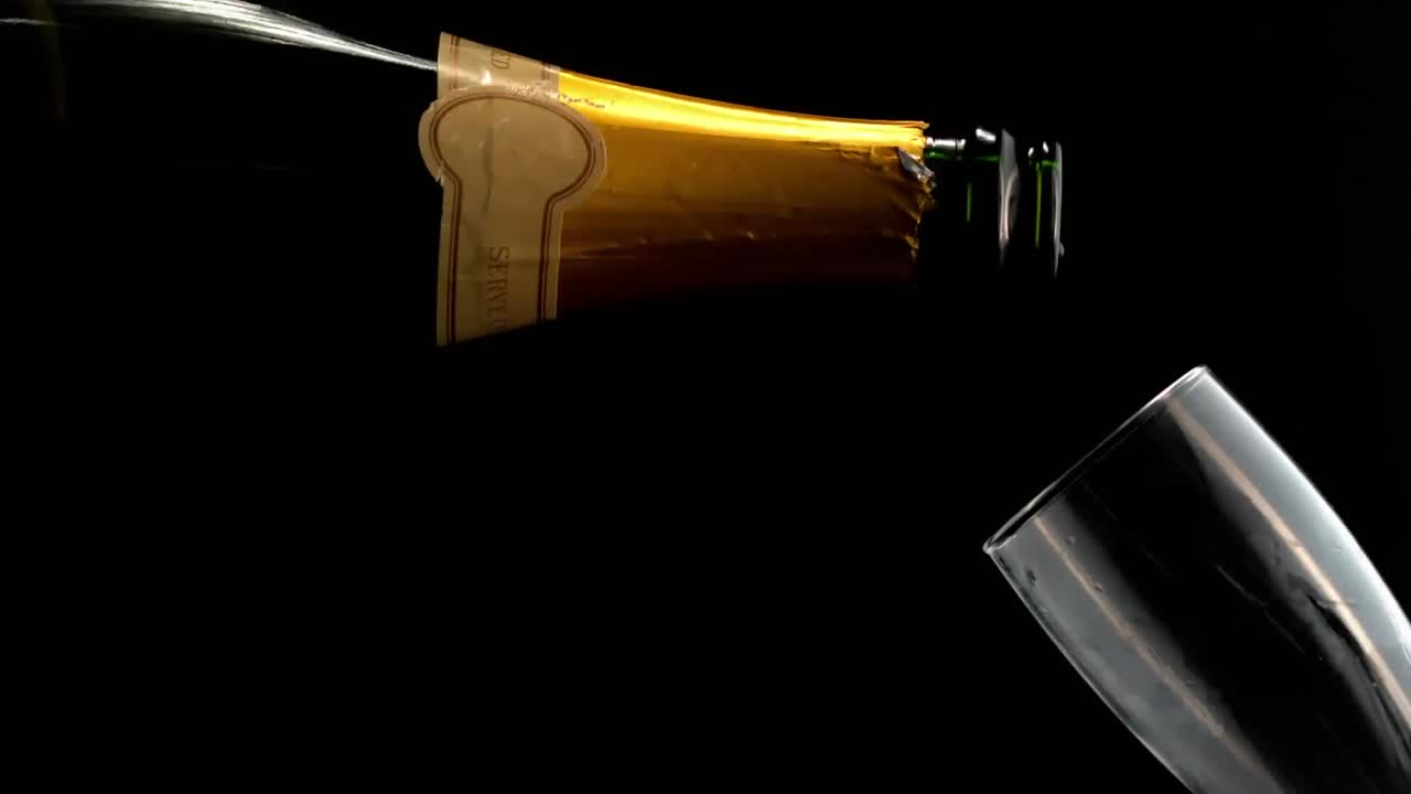 Animazione di carta che brucia su champagne che si versa in un bicchiere su sfondo nero