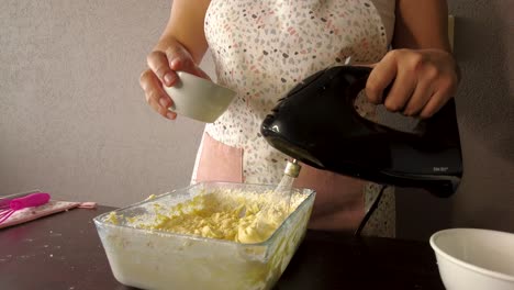 mujer latina usando un delantal preparando cocinar horneando un pastel vertiendo leche en la masa y mezclando
