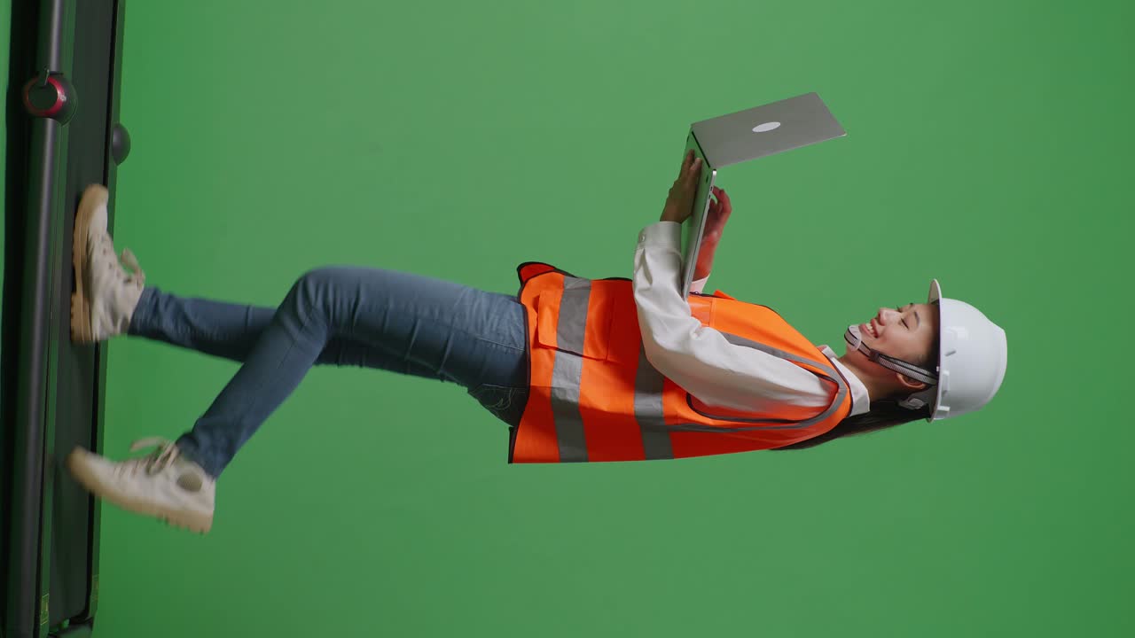 녹색 스크린 배경 스튜디오에서 는 동안 노트북에서 작업하는 안전 헬을 입은 아시아 여성 엔지니어의 측면 시각