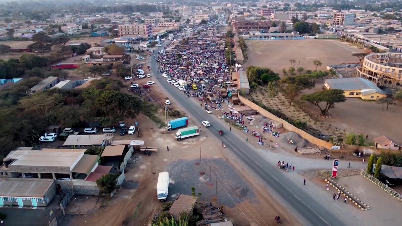 Splendida vista aerea di un mercato africano all'aperto con ombrelloni colorati, bancarelle affollate e gente del posto che commercia prodotti freschi sotto la calda luce del sole in Kenya.