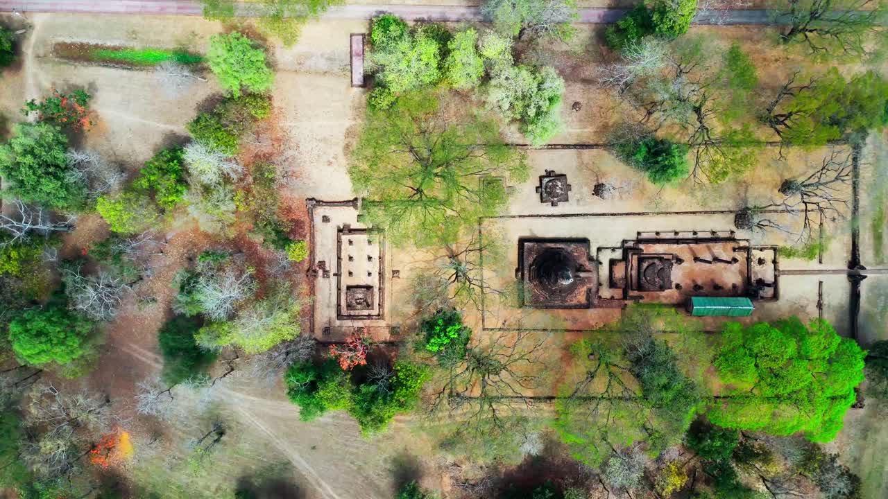 Aerial top down pan of Si Satchanalai Historical Park, Thailand, with ancient ruins surrounded by lush greenery