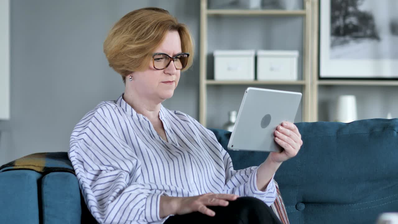 пожилая женщина реагирует на финансовые потери во время использования планшета