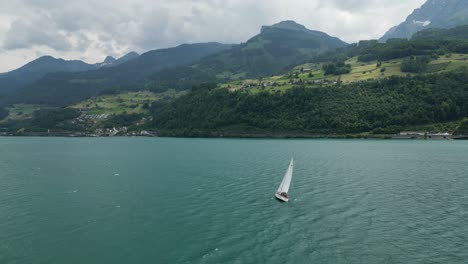 Wunderschöne-Yacht,-Die-Im-Ruhigen-Wasser-Des-Sees-Mit-Bergiger-Kulisse-Segelt