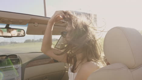 mujer disfrutando de un viaje por carretera soleado en un coche convertible