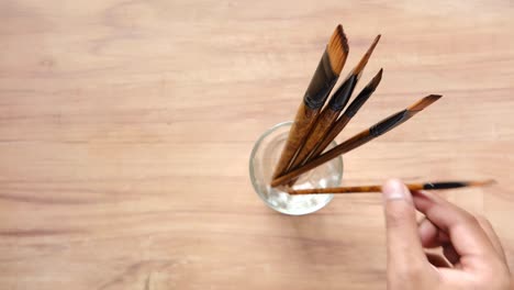 pinceles en un frasco de vidrio en una mesa de madera