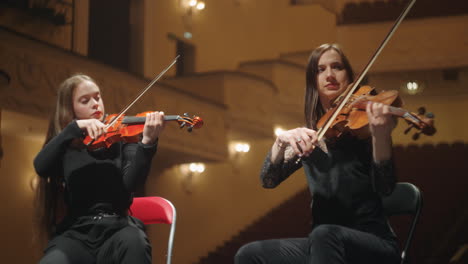 female violinists are playing music on scene of opera house two professional musicians in philharmonic hall