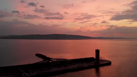 ascending drone shoot of a light house after a warm sunset