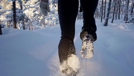 person hiking through snow in forest, snow chains on boots