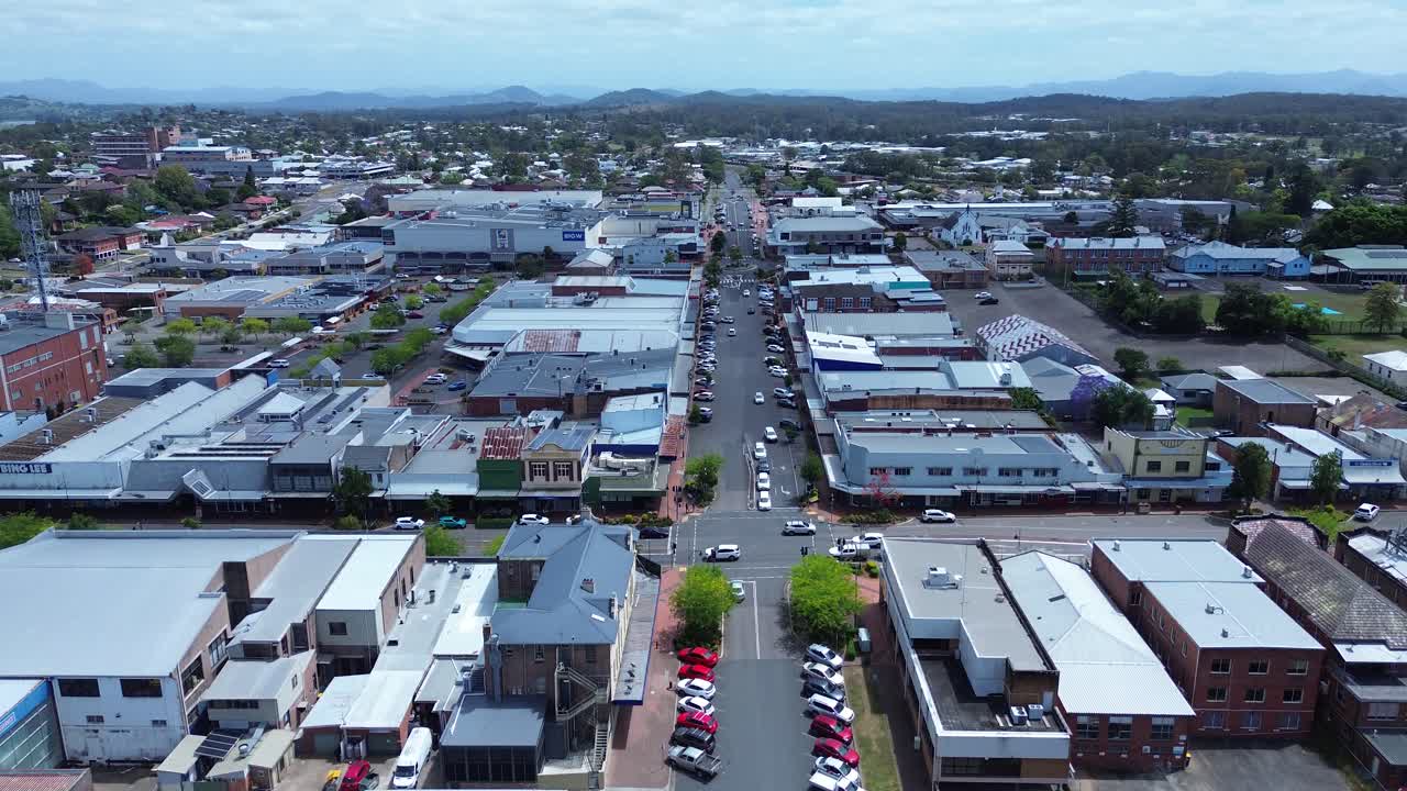 Drone aerial landscape of car vehicles and traffic driving on main road through downtown streets with commercial shop buildings and businesses in Taree NSW Australia travel tourism infrastructure