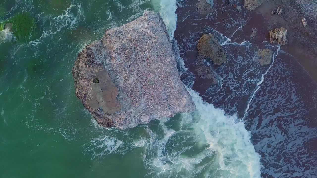 vista aérea de pájaro de edificios abandonados de fortificación costera en los fuertes del norte de karosta en la playa del mar báltico, olas salpicadas, puesta de sol de hora dorada, disparo de drones en órbita