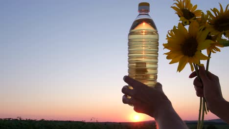 Plastic Bottle of Oil and Sunflower Flowers on a Background of Pink Sunset Plastic Bottle of Oil and Sunflower Flowers on a Background of Pink Sunset Slow Motion
