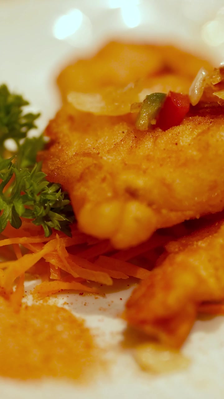 Primo piano di gamberi croccanti guarniti con erbe aromatiche e verdure sotto un'illuminazione calda.