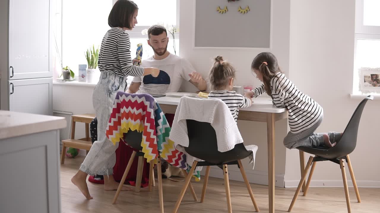 작은 아이들과 함께 집에서  ⁇ 색 부 ⁇ 에서 함께 아침 식사를하는 행복한 젊은 가족. 팬케이크를 먹고