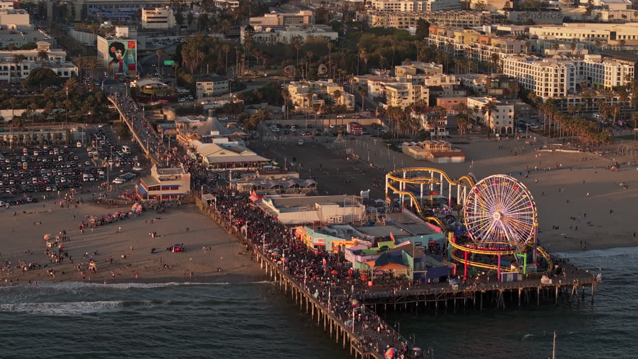 Santa Monica California Aerial v19 birds eye view flyover a crowded pier featuring iconic amusement park, state beach and downtown cityscape at sunset - Shot with Mavic 3 Pro Cine - May 25th 2024